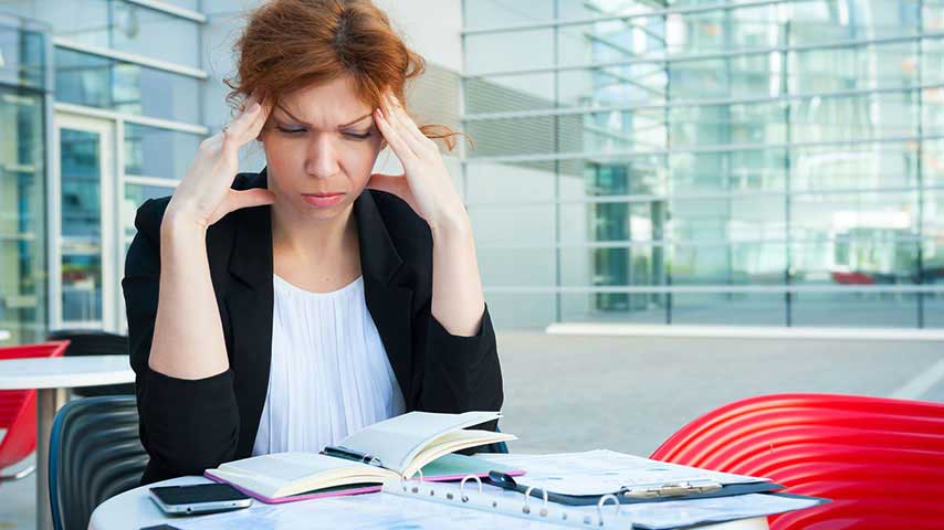 Frustrated and tired business woman sitting in modern background. Need to hire a PowerPoint designer.